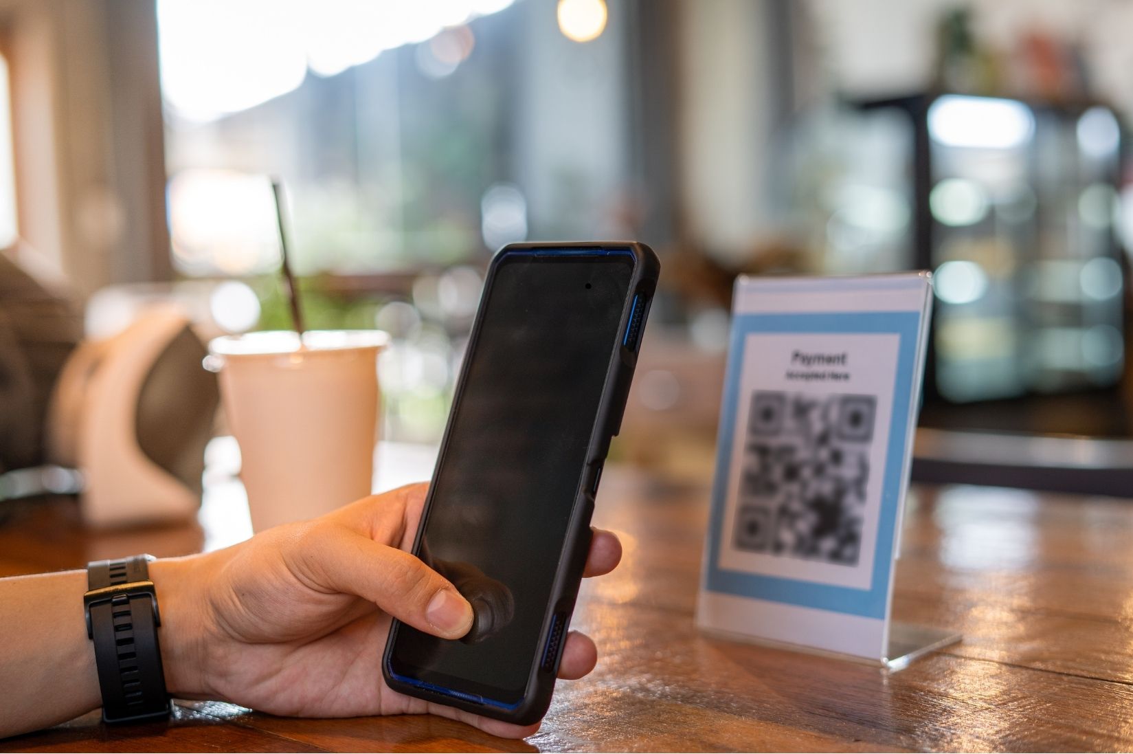 A customer scanning a QR code on a table tent in a cafe