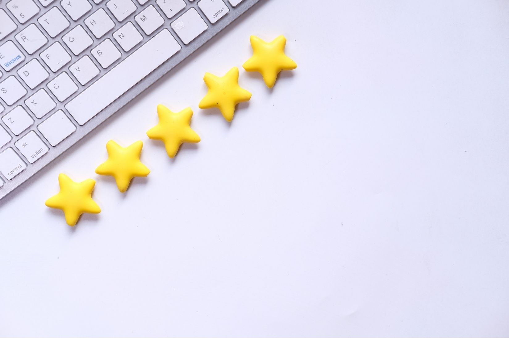 Five yellow stars next to a keyboard on a white desk
